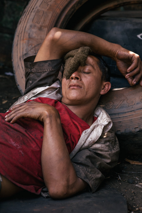 Photo A cowboy grabs a young cow by the tail in the corral in order to castrate it. Right, a mechanic worker snoozes in the shade of the midday sun. 