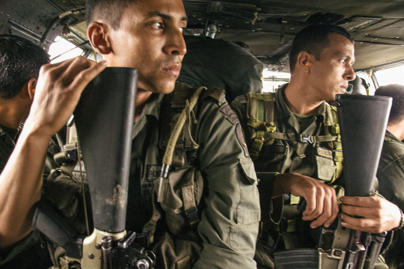 Photo Anti-narcotics police aboard a Blackhawk helicopter on a coca plantation reconnaissance mission. Right, models getting ready back stage at Colombia Fashion week. Both July 2010 